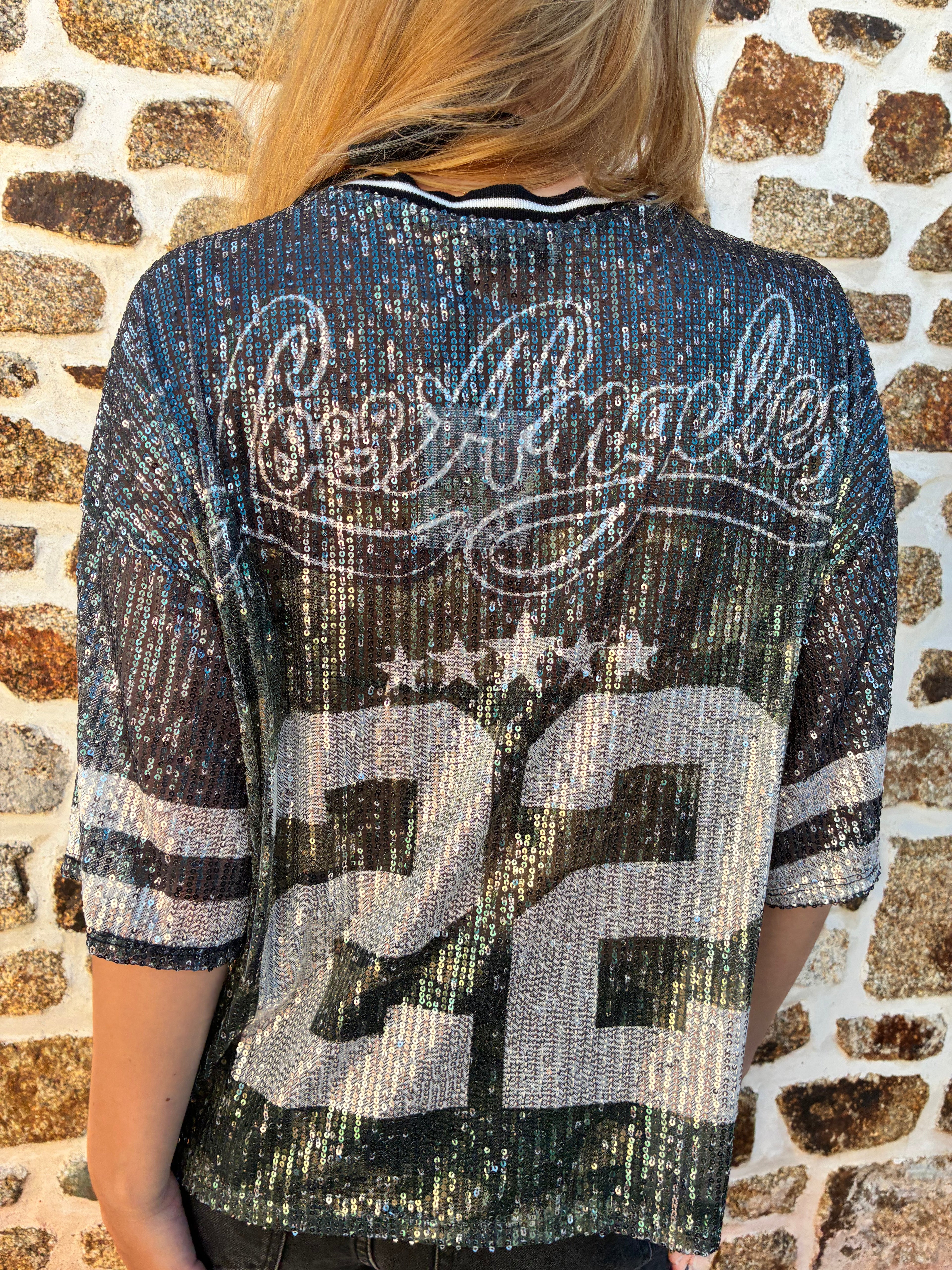 Haut à paillettes Le Vestiaire, élégant haut brillant avec manches longues, porté sur un mannequin blanc.